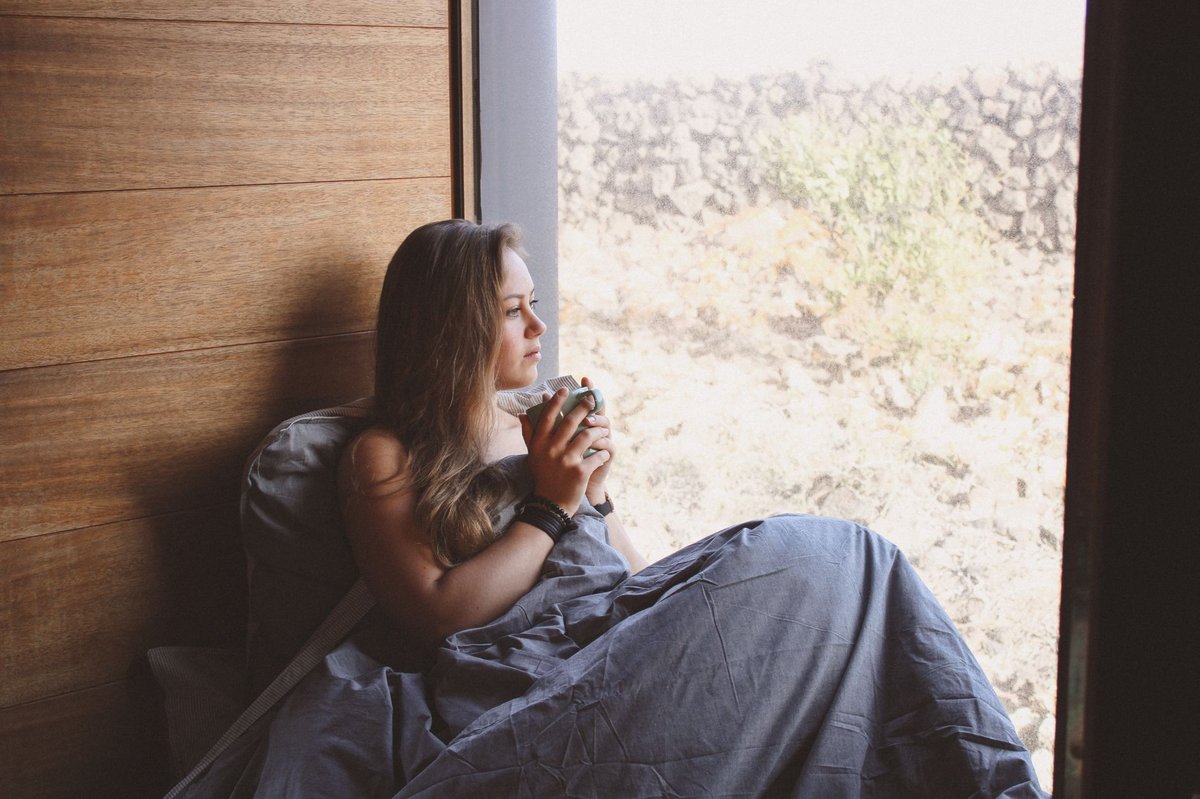 Person resting with a warm drink by a window