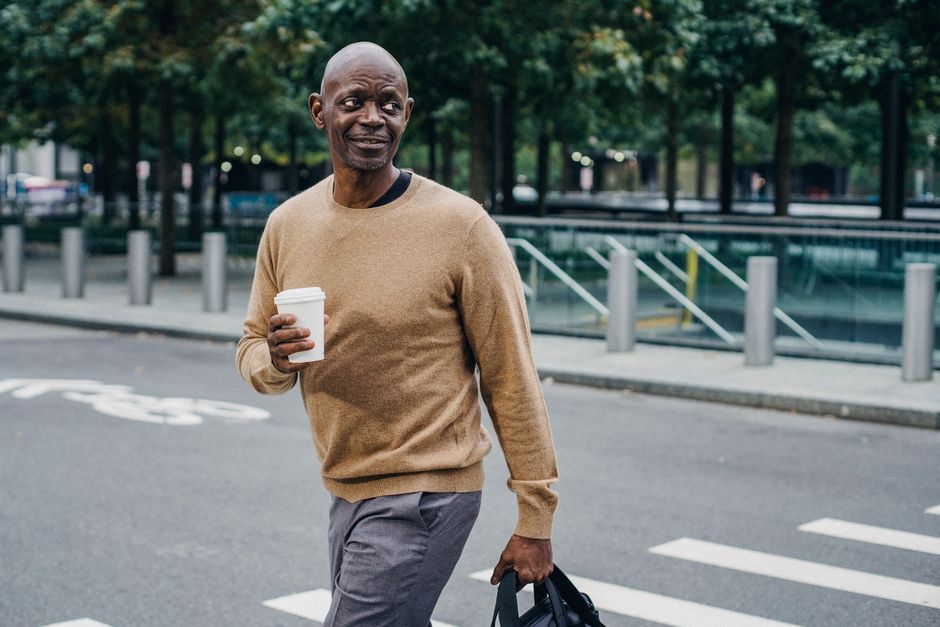 A man walking outdoors with a coffee