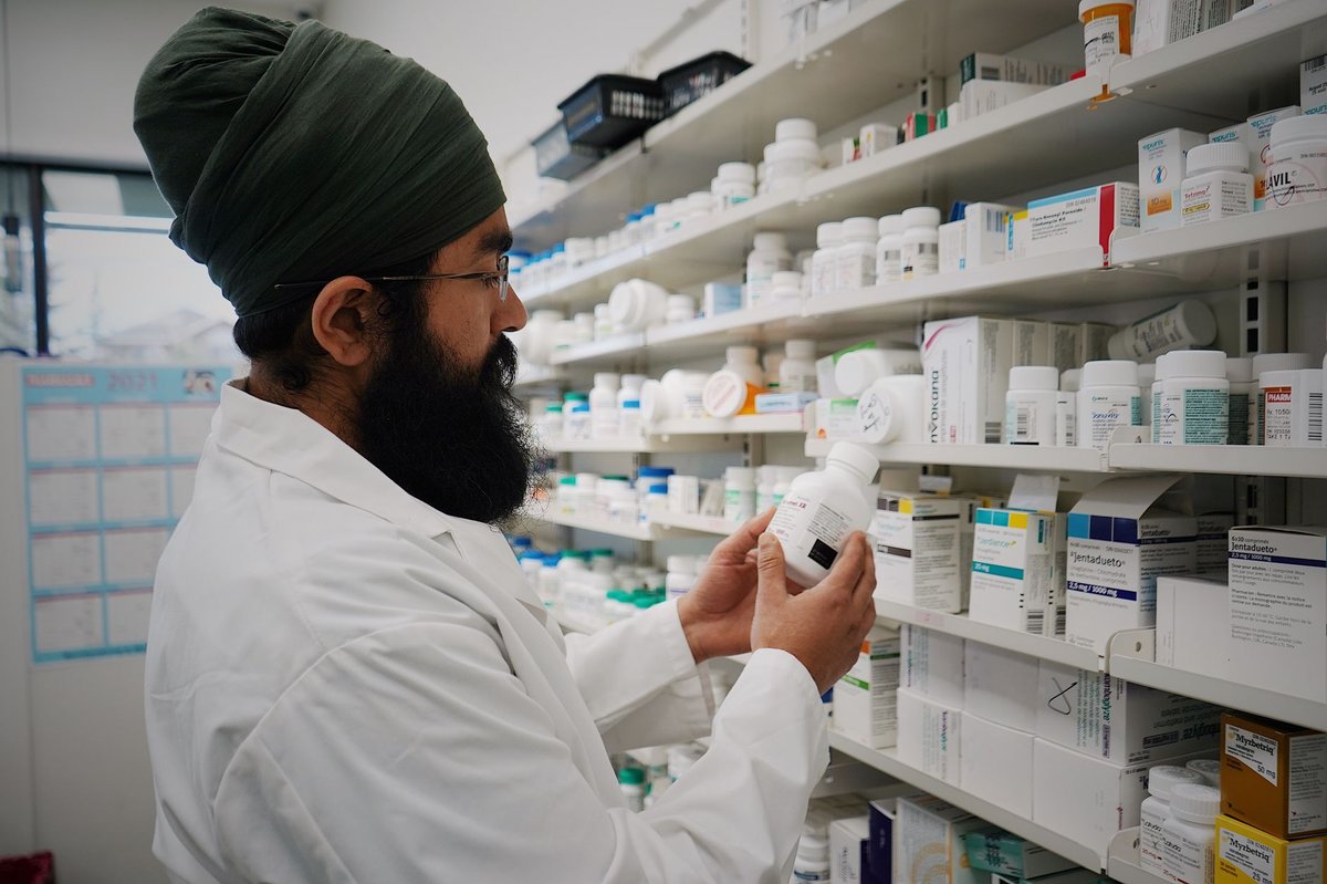 Pharmacist standing in front of shelves of medicines
